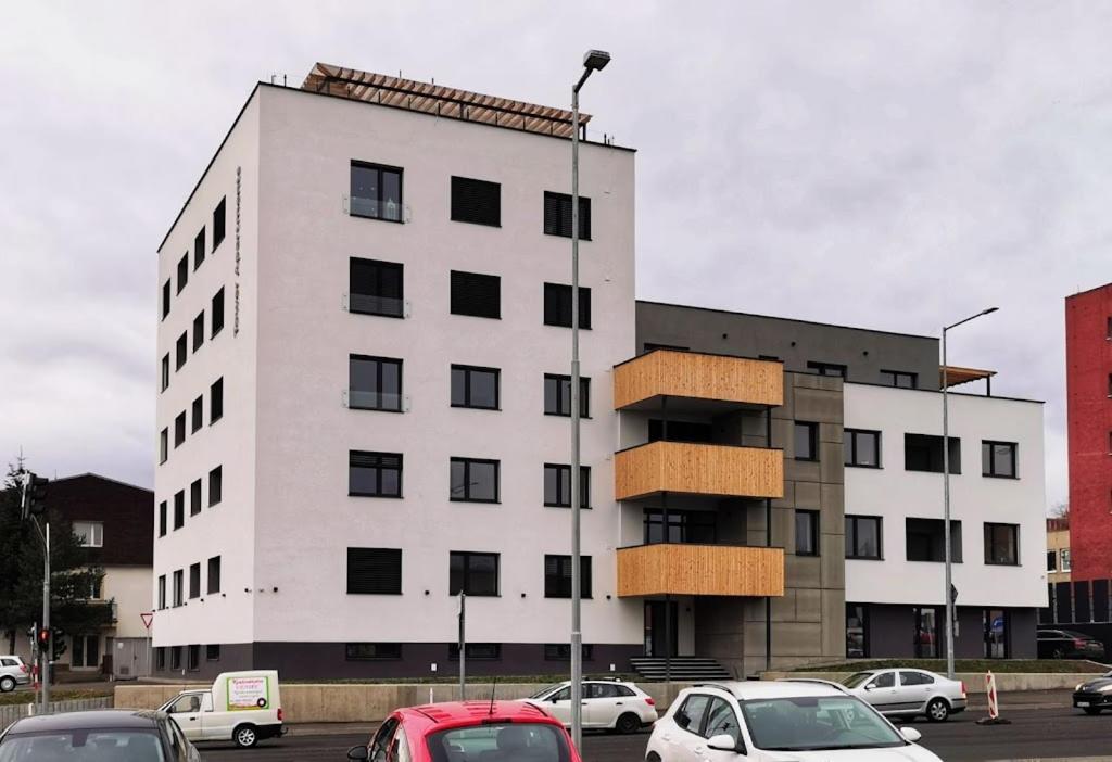 a white building with cars parked in a parking lot at Tower Apartments in Spišská Nová Ves