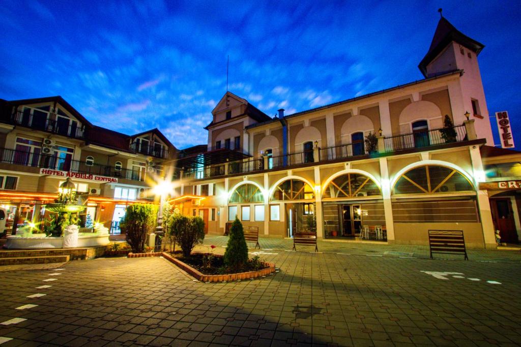 um grande edifício com um pátio à noite em Hotel Apollo Central em Sibiu