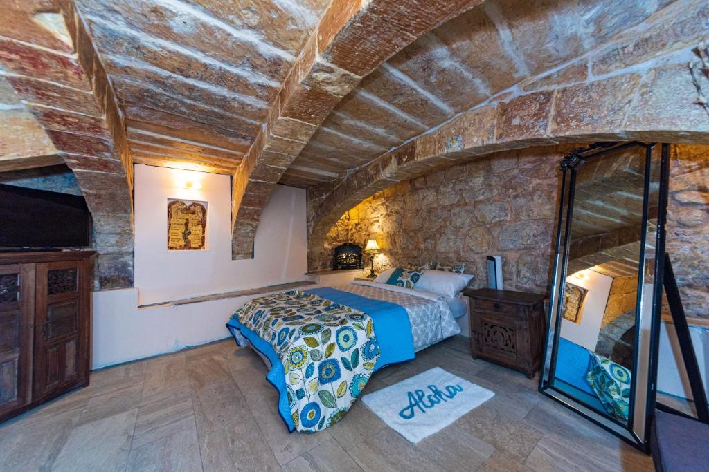 a bedroom with a bed and a stone wall at Valletta Traditional Townhouse in Valletta