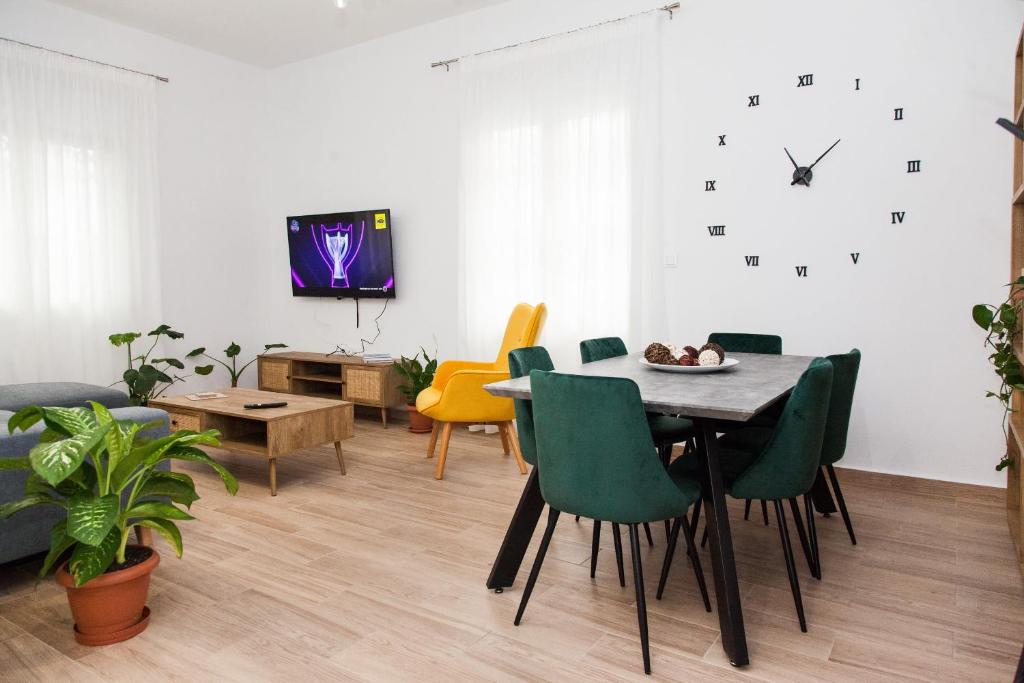 a living room with a table and chairs and a clock at Beautiful new apartment in Petralona in Athens