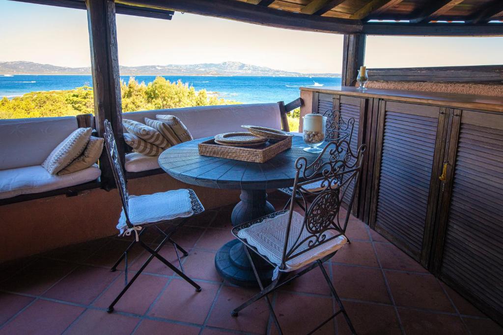 a table and chairs on a porch with a view of the ocean at Splendido appartamento Vista Mare Porto Rotondo in Porto Rotondo