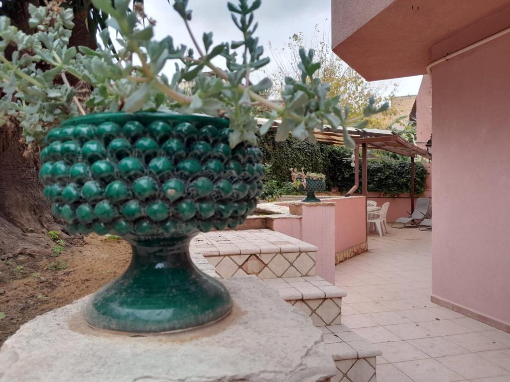 a green glass vase with a plant in it at Oasi home in Casteldaccia