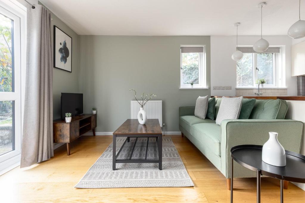 a living room with a green couch and a table at The Camberwell Apartment in London