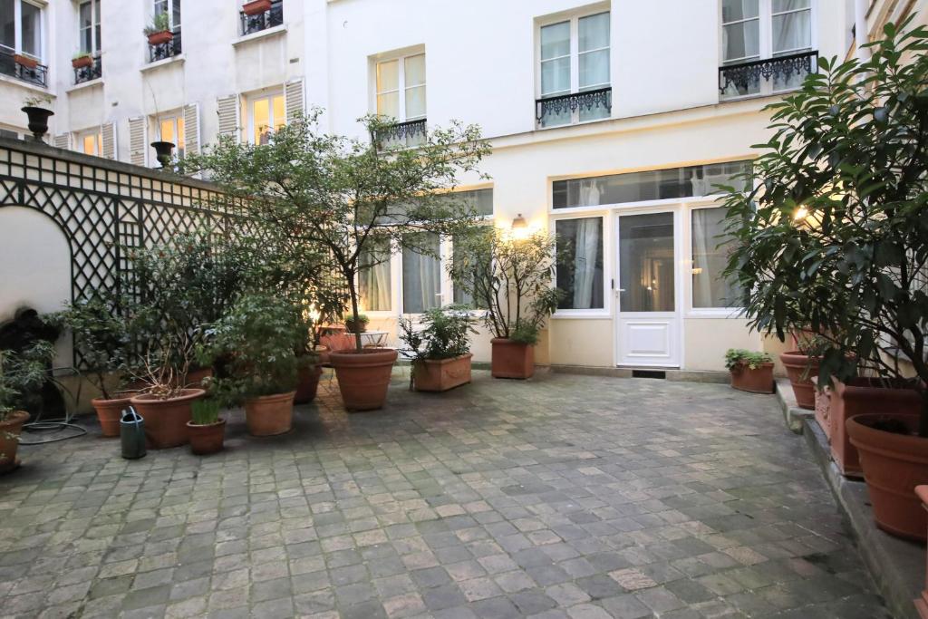 une cour avec des plantes en pot devant un bâtiment dans l'établissement Victoire I, à Paris