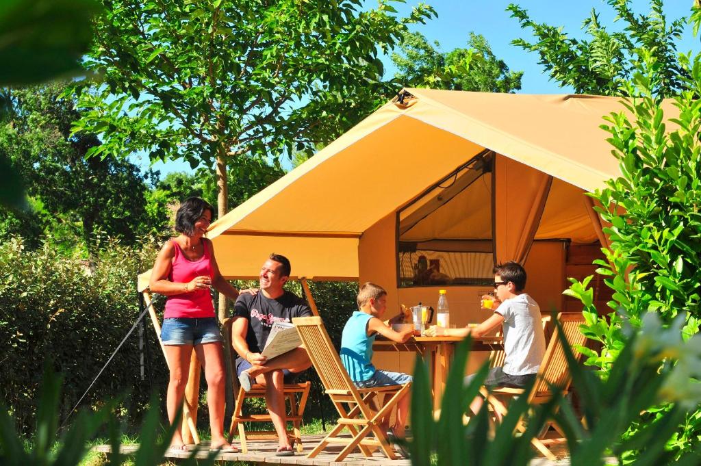 a group of people sitting at a table in front of a tent at Camping Capfun La Bretèche in Les Épesses
