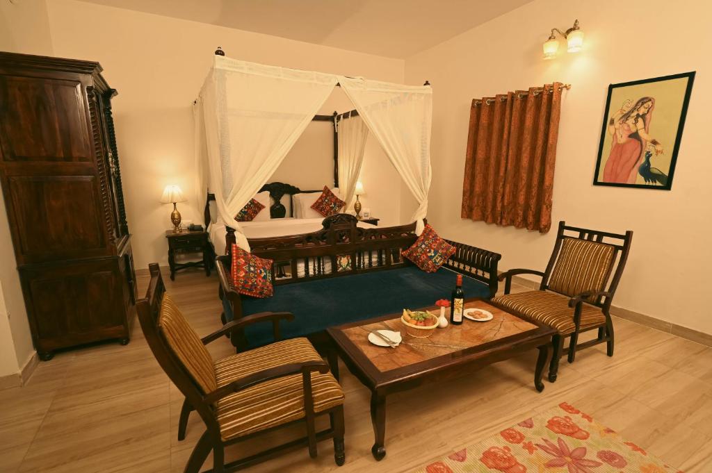 sala de estar con cama, mesa y sillas en ClarksInn Suites Ranthambhore, en Sawāi Mādhopur