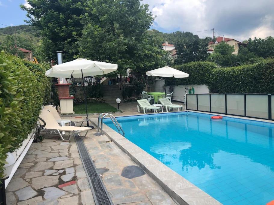 uma piscina com dois guarda-sóis e cadeiras ao lado em La maisonnette Villa Katerina em Krionérion