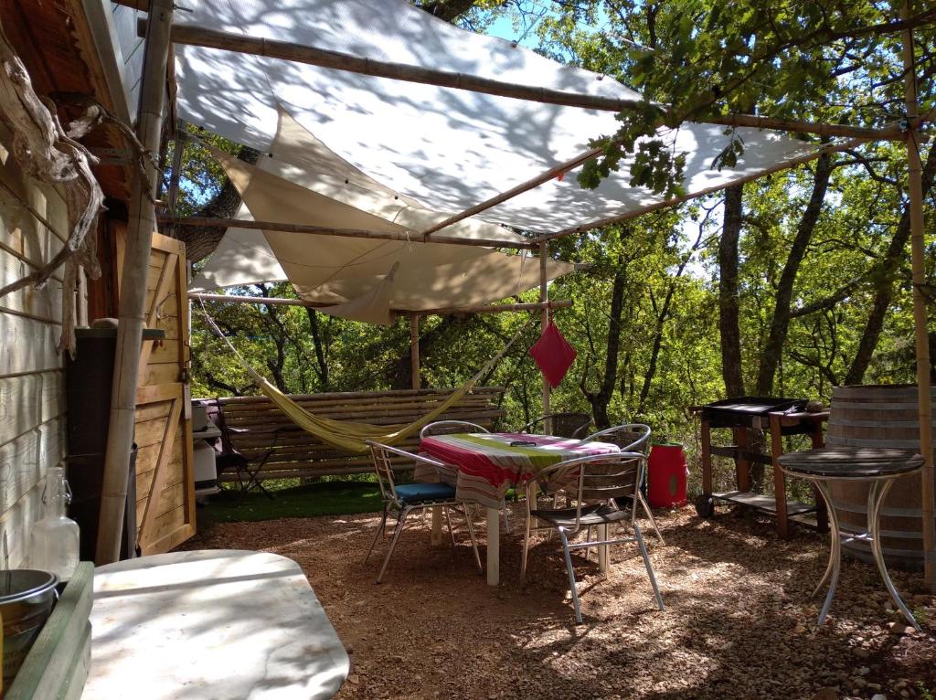 a patio with a table and chairs under a tent at Cabane sous les Chênes in Montagnac
