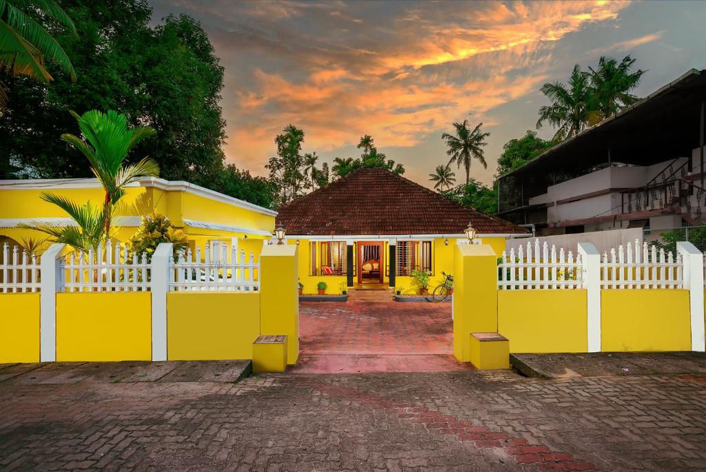 a yellow house with a white fence in front of it at The Mayflower - Heritage Villa in Alleppey