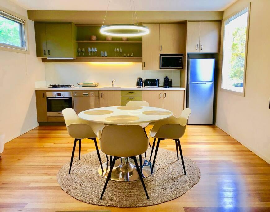 a kitchen with a table and chairs and a refrigerator at Hepburn Hideaway Villa ~ Hepburn / Daylesford in Hepburn Springs