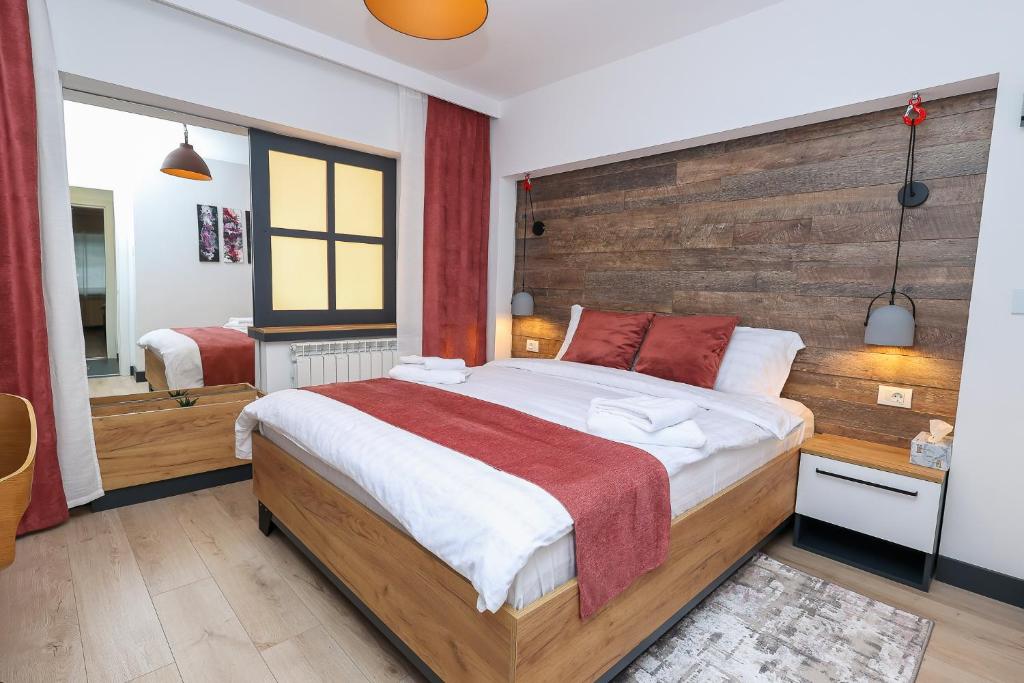 Schlafzimmer mit einem großen Bett mit einem Kopfteil aus Holz in der Unterkunft Ioana Residence Bucovina in Câmpulung Moldovenesc