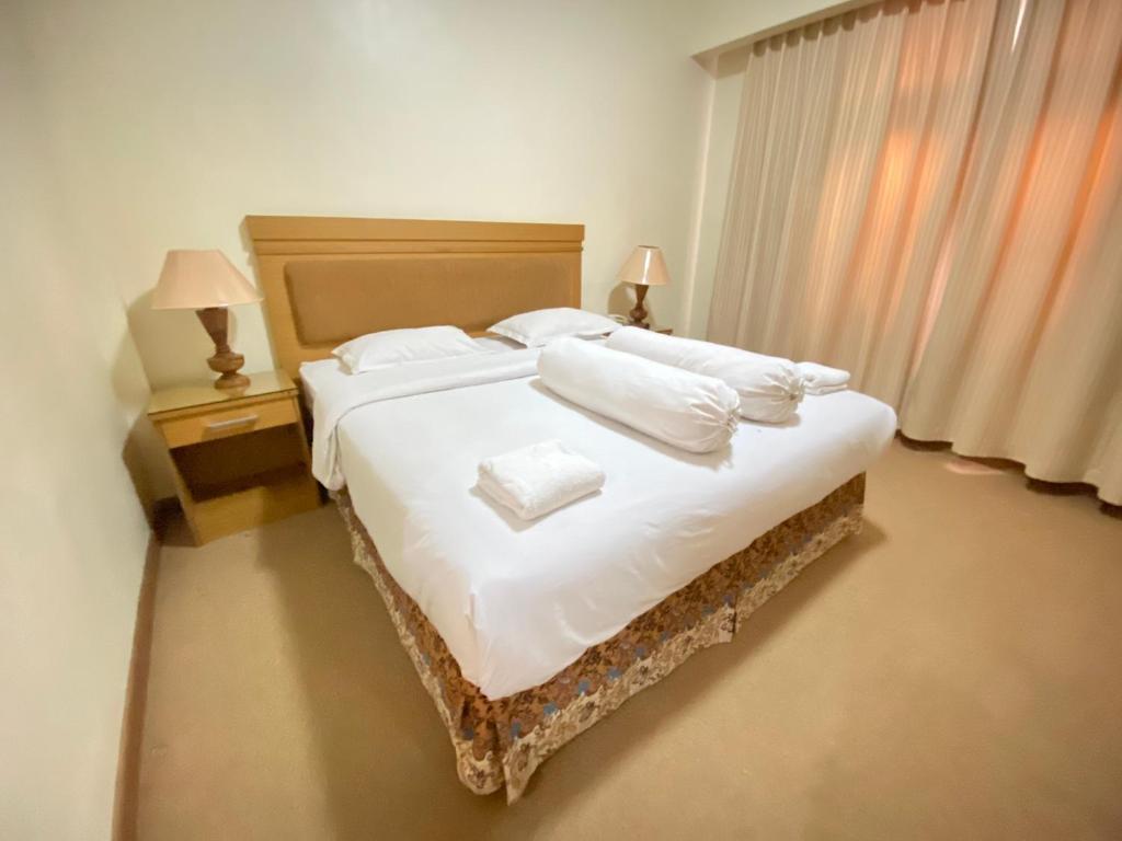 a bedroom with a large bed with white sheets and pillows at Lilianto Hotel Polewali Mitra RedDoorz in Campalagiang