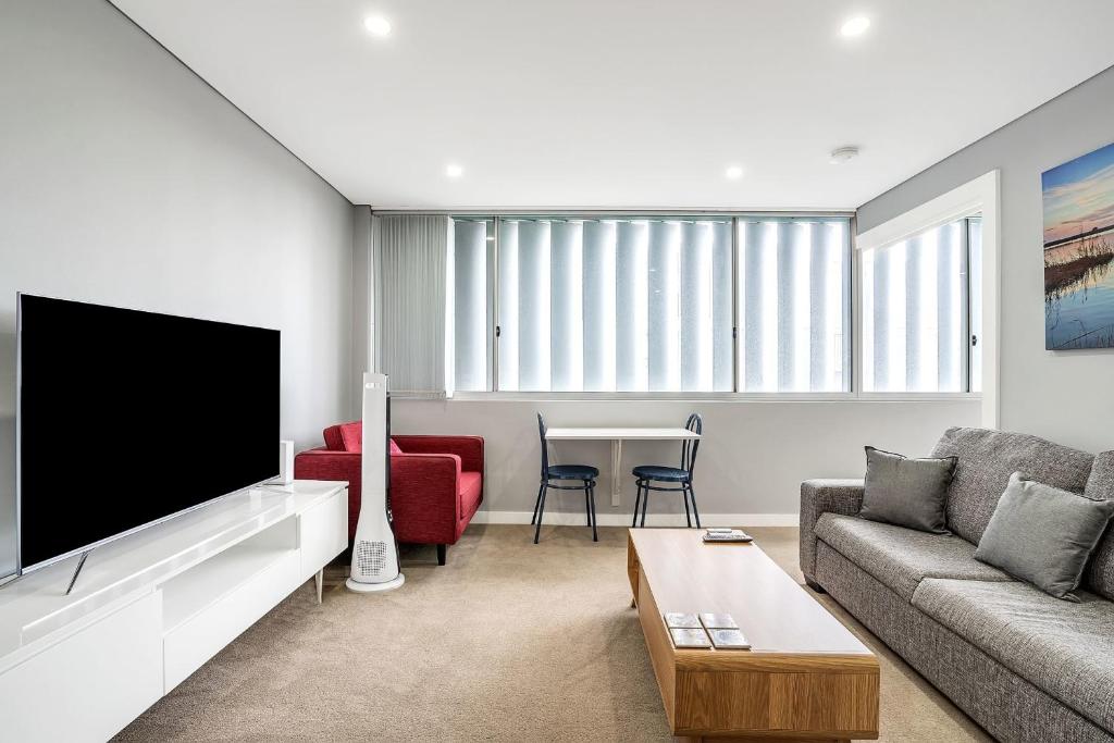 a living room with a couch and a tv at Bright 1 Bedroom unit in the heart of Manly in Sydney