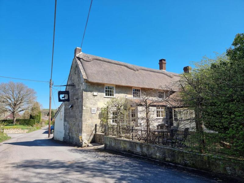 an old stone house sitting on a street at The Forester in Shaftesbury