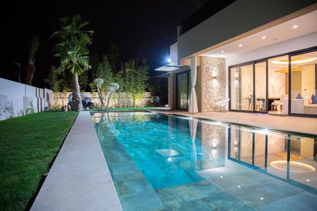 een zwembad voor een huis 's nachts bij Magnifique nouvelle Villa avec Piscine chauffée in Marrakesh
