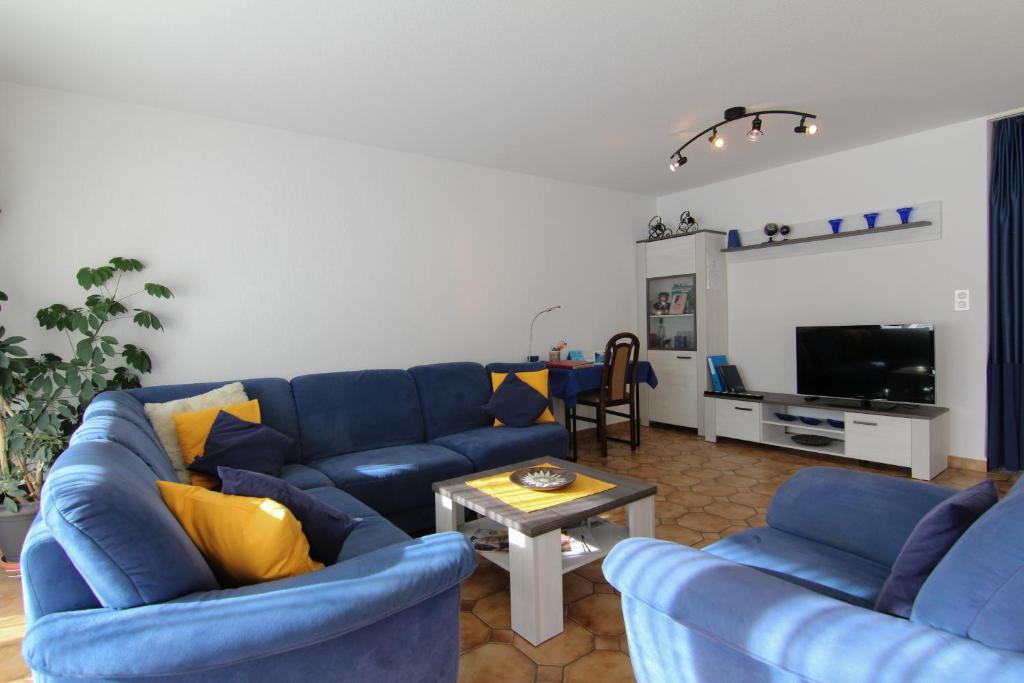 uma sala de estar com sofás azuis e uma mesa em Casa Yolanda Familienwohnung Mireille em Fieschertal