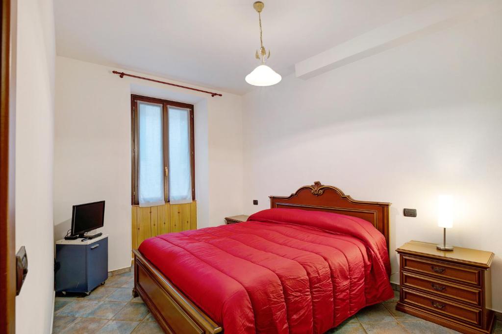 a bedroom with a red bed and a television at Casa Giola Omegna in Omegna