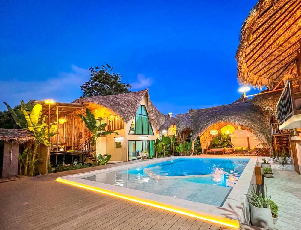 une villa avec une piscine la nuit dans l'établissement Varni Homestay, à Phatthalung
