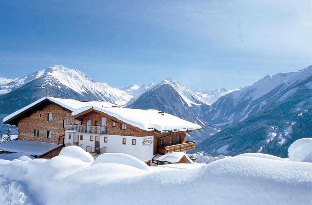 um edifício coberto de neve no topo de uma montanha nevada em Pension Sonneck em Neukirchen am Grossvenediger