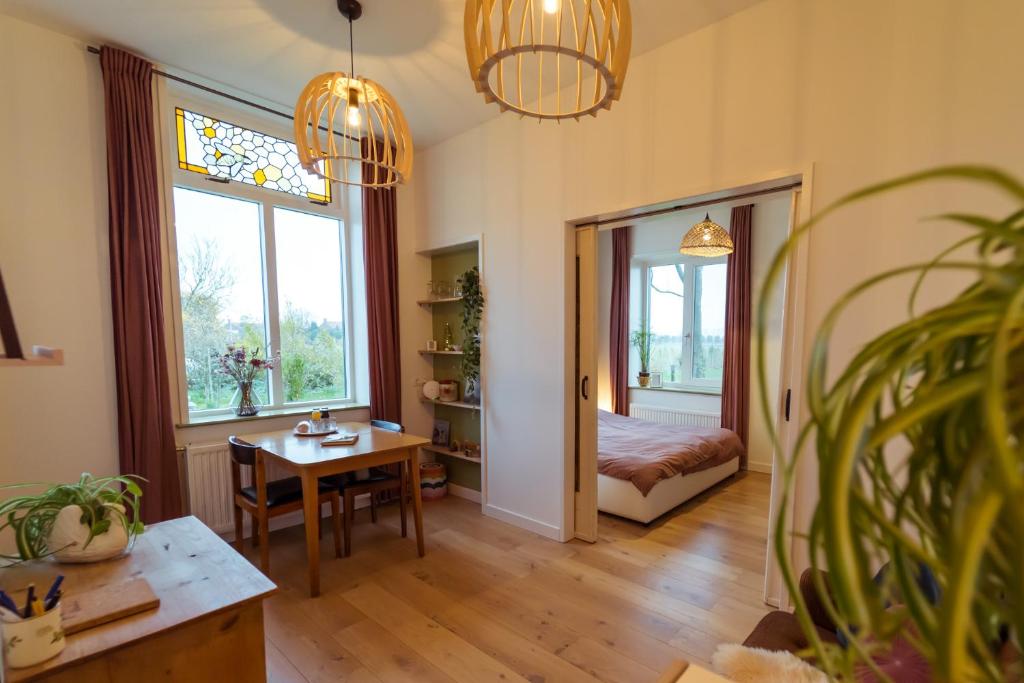 Cette chambre dispose d'une table, d'un lit et de fenêtres. dans l'établissement Huisje op Bioboerderij, kust, polder en rust, à Hoofdplaat