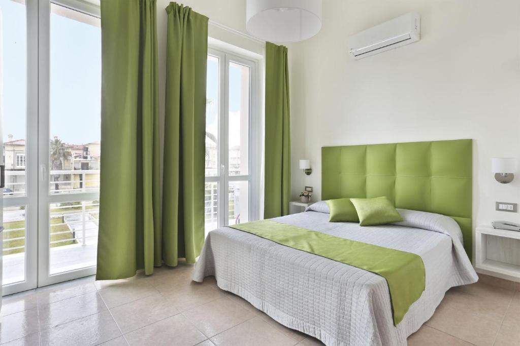 a bedroom with a green bed and a large window at Hotel Nuovo Tirreno in Lido di Camaiore