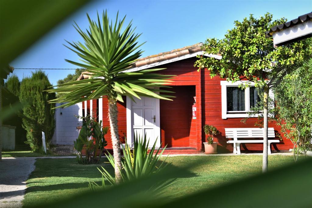 una casa roja con un banco y una palmera en Kontiki Bungalows El Palmar en El Palmar
