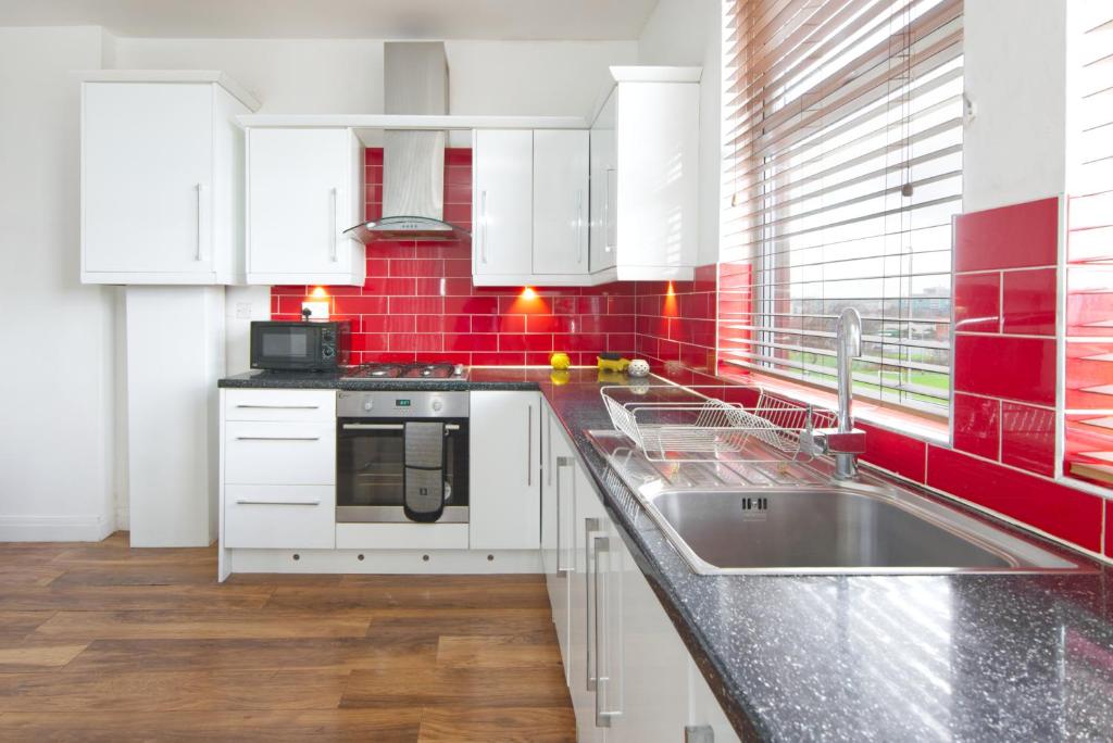 eine Küche mit weißen Schränken, einer Spüle und roten Fliesen in der Unterkunft spacious apartment close to city centre with free secure parking in Leeds