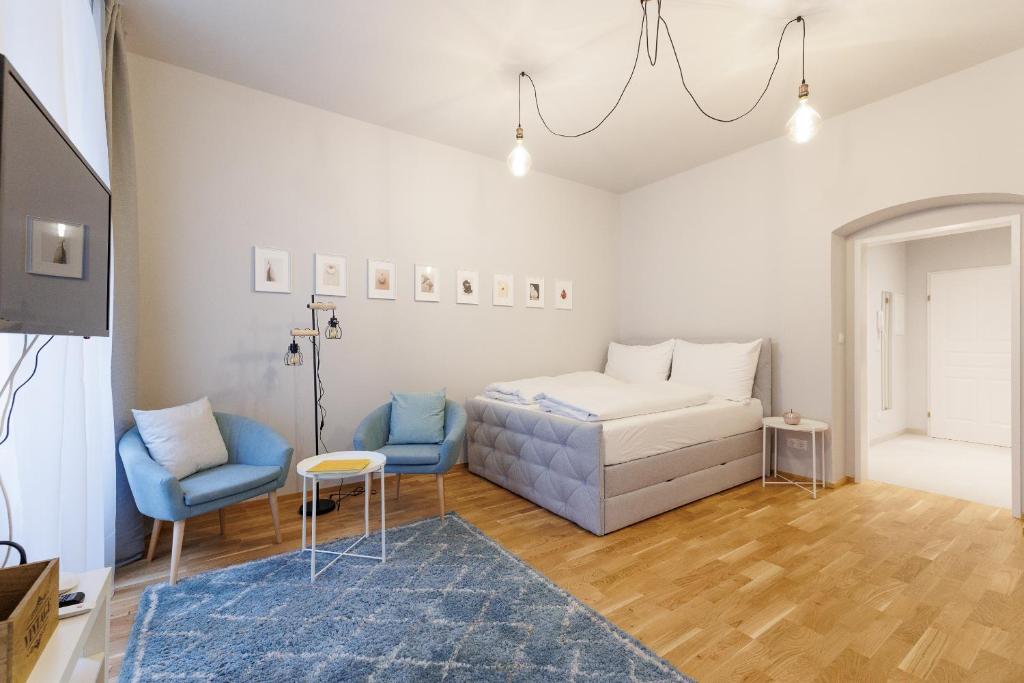 sypialnia z łóżkiem i dwoma niebieskimi krzesłami w obiekcie Vienna City Apartments Krongasse w Wiedniu