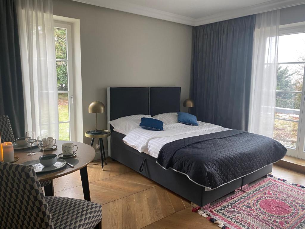 1 dormitorio con cama, mesa y ventanas en Kraków Green Hill Luxury Apartment en Balice