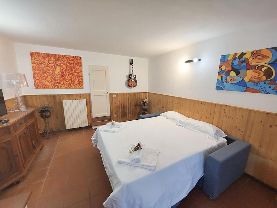 Un dormitorio con una cama y una guitarra en la pared en Villa Tutti i colori del Chianti, en Linari