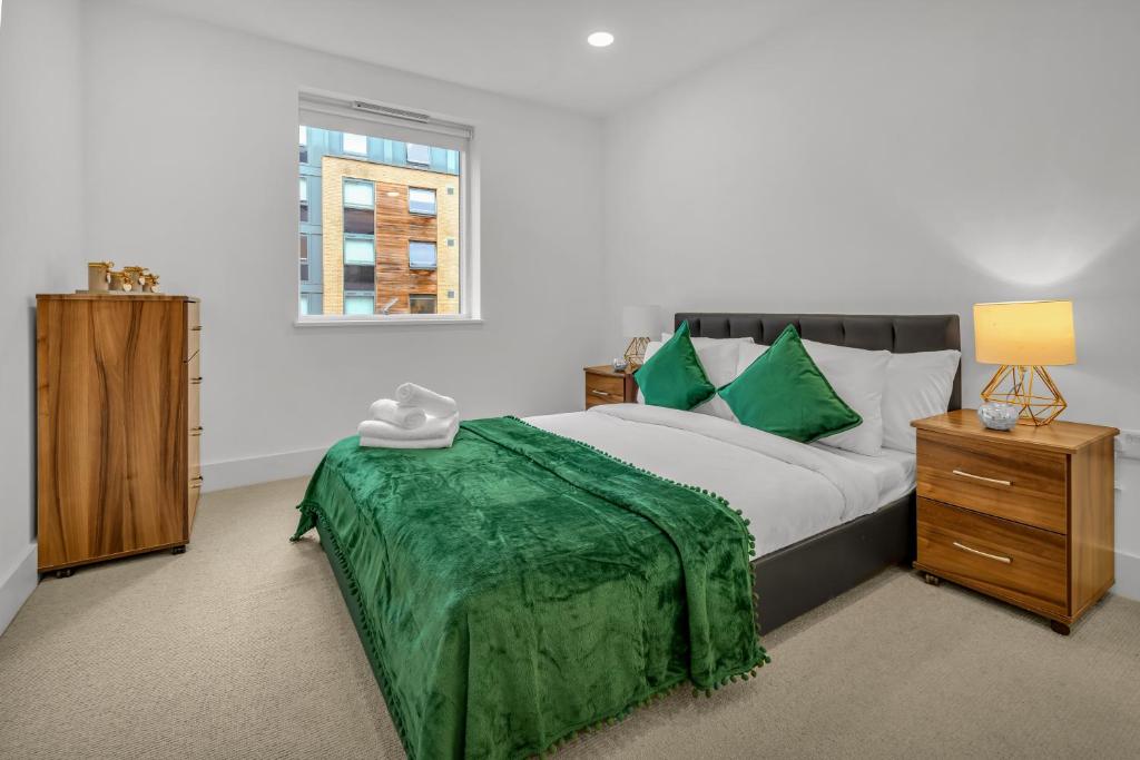 a bedroom with a bed with green sheets and a window at One Bedroom Serviced Apartment in Islington in London
