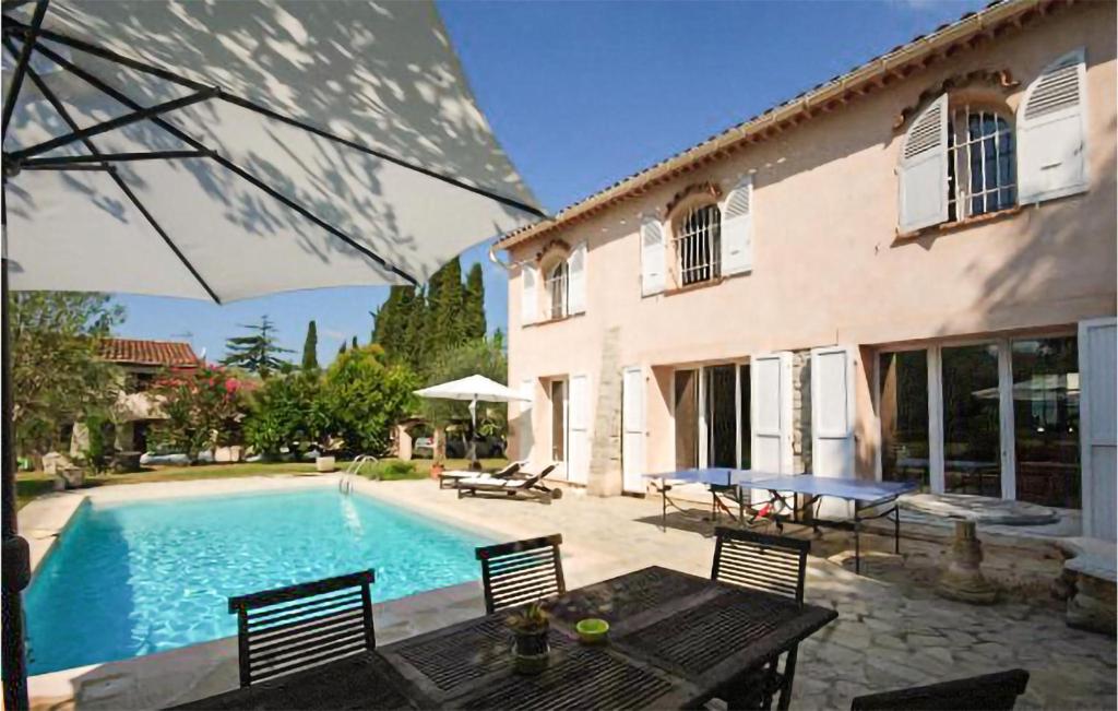 a pool with a table and chairs and a house at Gorgeous Home In Mouans-sartoux With Heated Swimming Pool in Mouans-Sartoux
