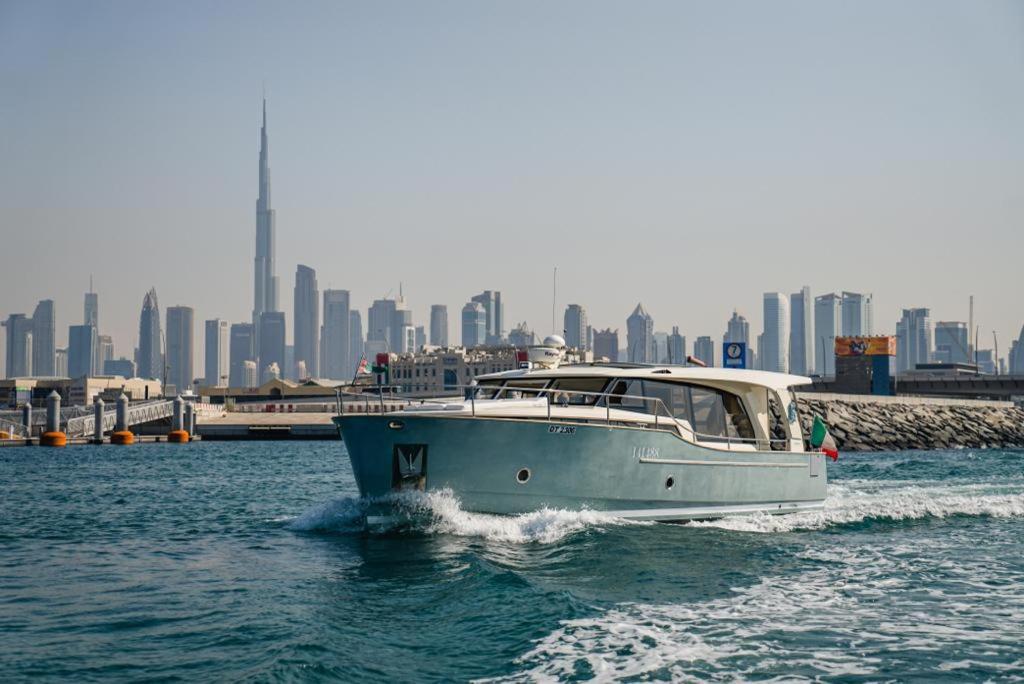 Stella Romana Yacht في دبي: قارب في الماء مع مدينة في الخلفية