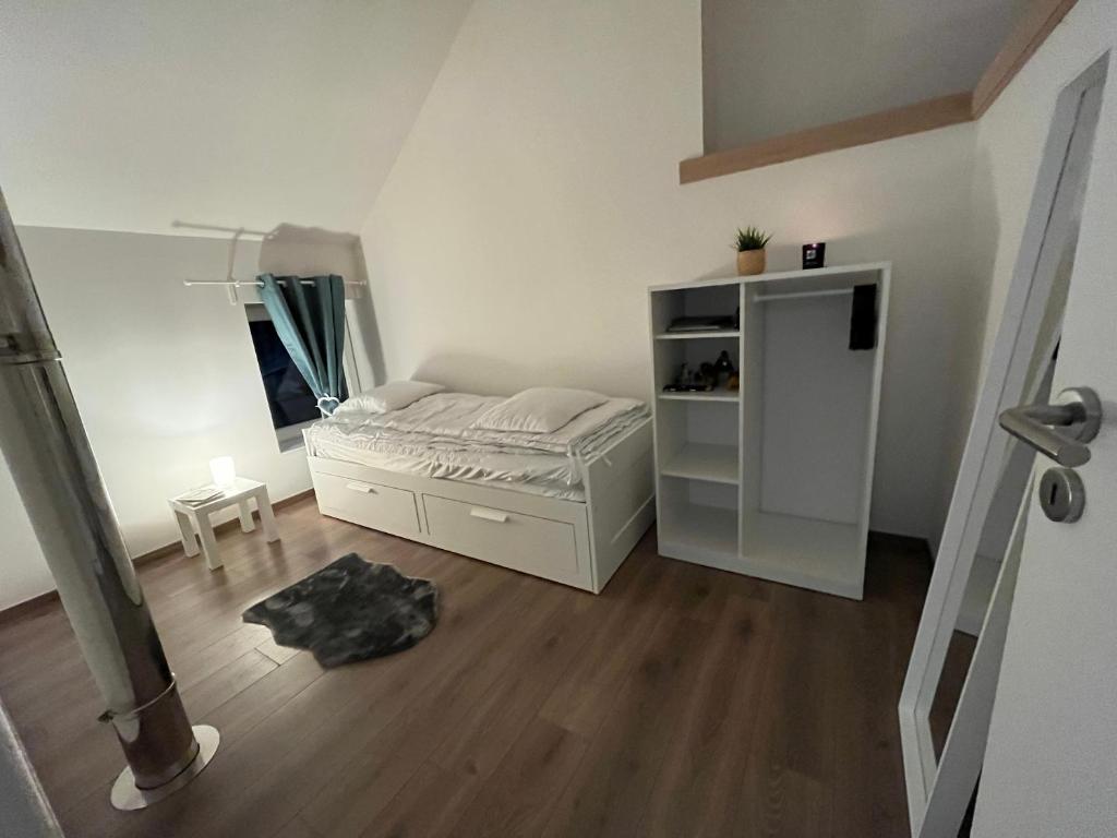 een kleine slaapkamer met een bed en een houten vloer bij Chez Charly et Milo - La maison du bonheur in Somme-Leuze
