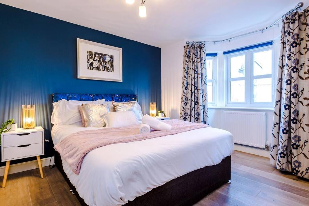 ein Schlafzimmer mit einem großen Bett mit blauer Wand in der Unterkunft Luxury detached home in 168 Upton Grange in Mollington