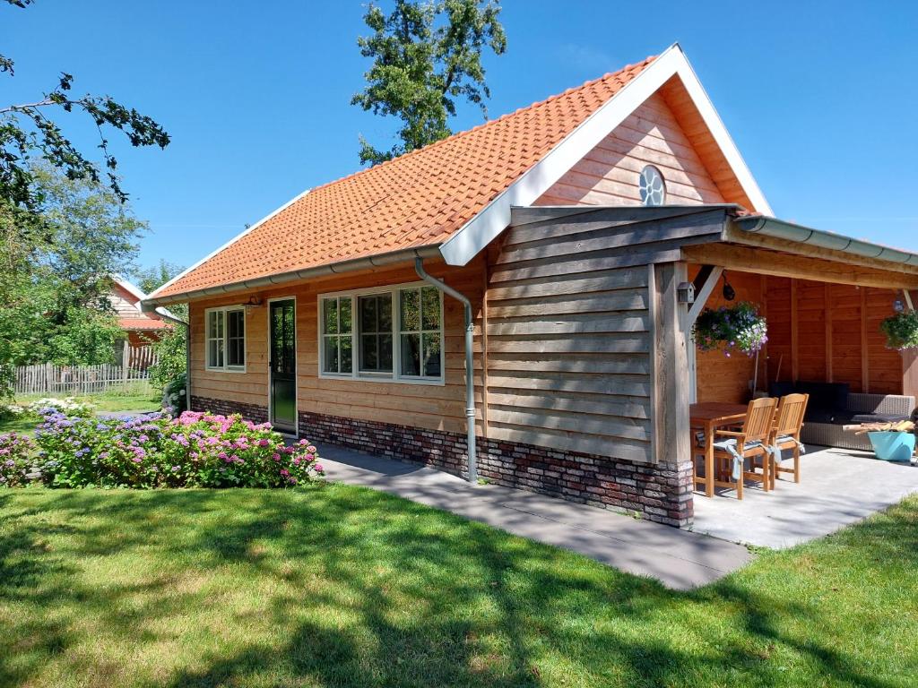 een klein huis met een patio en een gazon bij Lodges near the Rhine - Sustainable Residence in Hazerswoude-Rijndijk