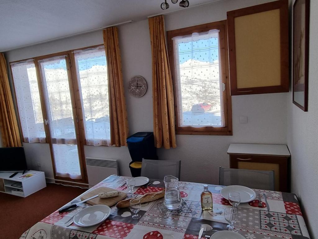 d'une salle à manger avec une table, des chaises et des fenêtres. dans l'établissement Studio pratique proche pistes avec terrasse et animaux admis - FR-1-181-2227, à La Plagne Tarentaise