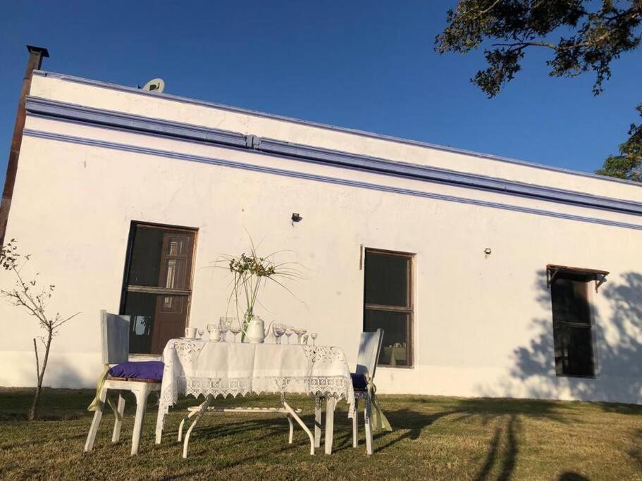 una mesa y sillas frente a un edificio blanco en Uruguay Casa de Época Campestre, en Mercedes