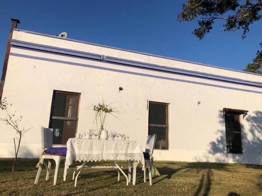 a table and chairs in front of a white building at Uruguay Casa de Época Campestre in Mercedes