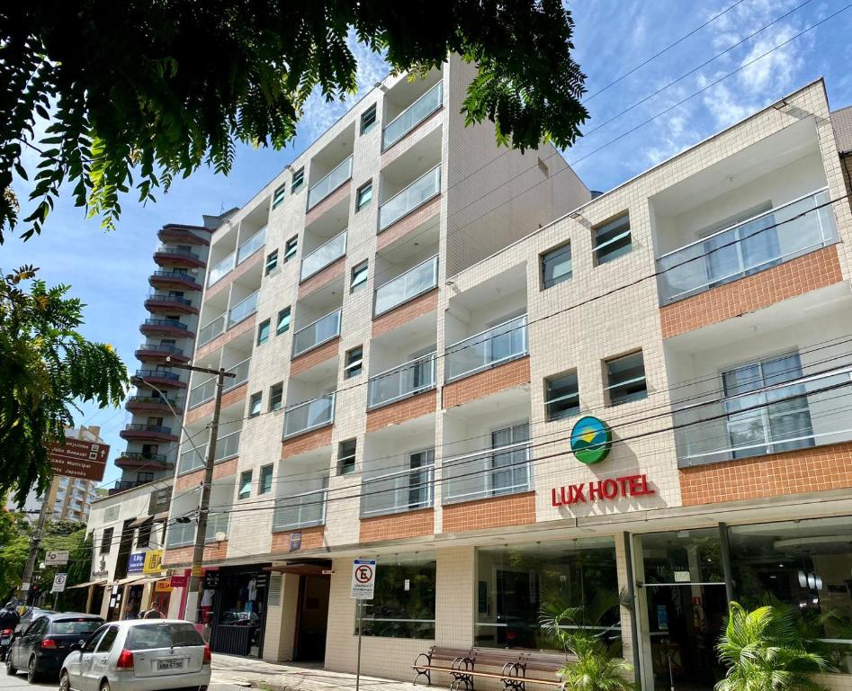 a building on a street with cars parked in front of it at Hotel Lux in Poços de Caldas