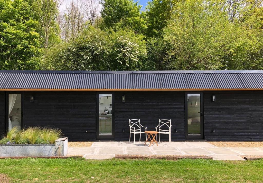 una mesa y sillas frente a un edificio negro en The Hopper Huts, en Faversham