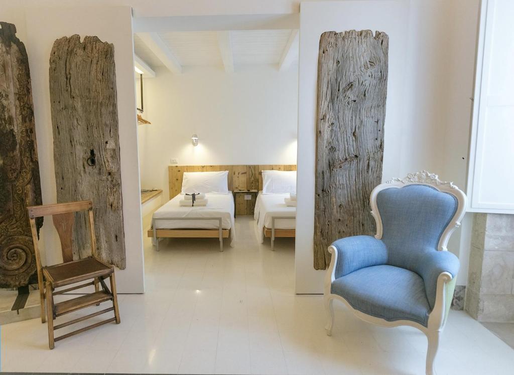 シラクーサにあるDione Apartments by Dimore in Sicily Ortigiaのベッド2台と青い椅子が備わる客室です。