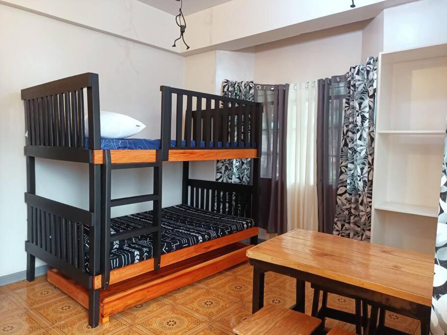 Zimmer mit 2 Etagenbetten und einem Tisch in der Unterkunft Studio Unit with Own Cr & Kitchen - Unit 303 in Baguio City