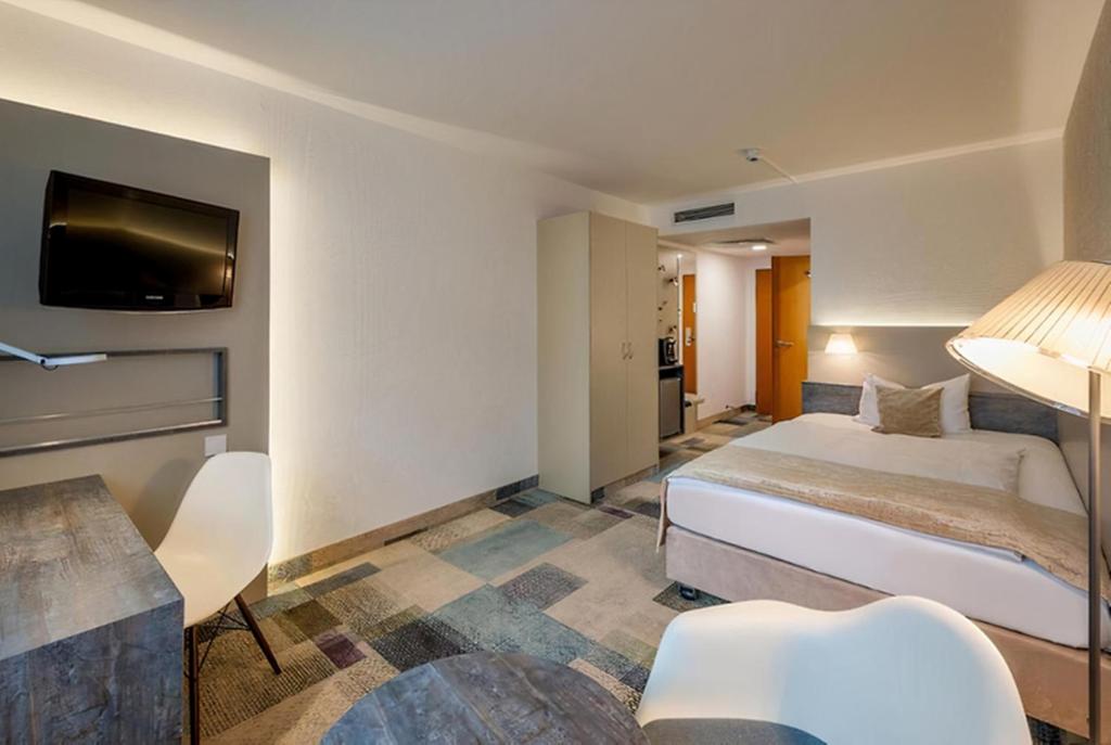 a hotel room with a bed and a flat screen tv at PLAZA INN Regensburg in Regensburg