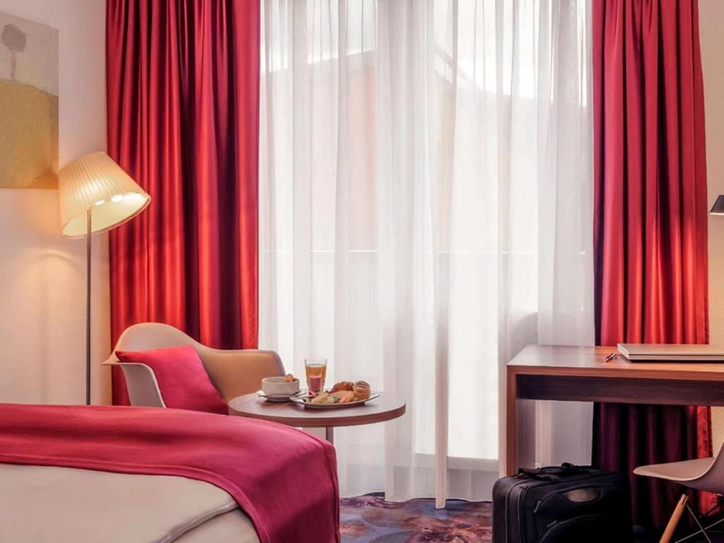 a hotel room with a bed and a table and a desk at PLAZA INN Regensburg in Regensburg