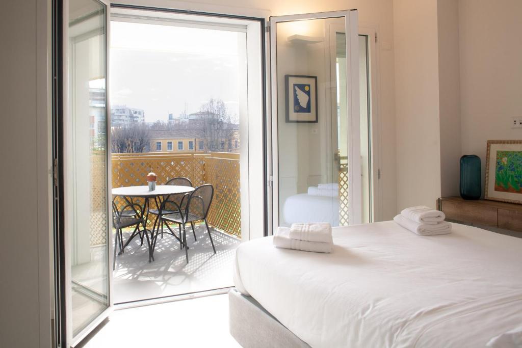 a bedroom with a bed and a balcony with a table at BnButler - Flavio Gioia, 5 - Appartamento con Vista, Citylife in Milan