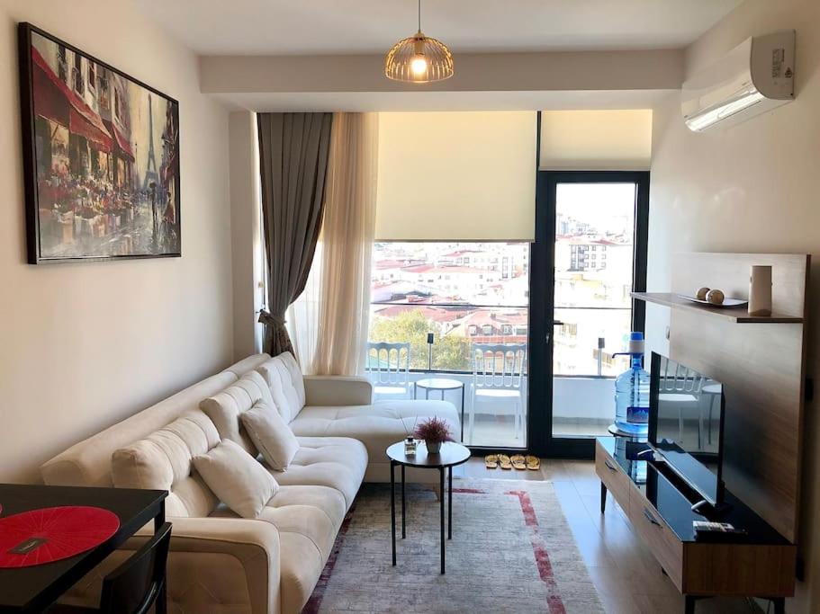 een woonkamer met een witte bank en een tafel bij Secured Lux 1 + 1 apartment - Gym, Sauna & Parking ( EMP 142 ) in Esenyurt