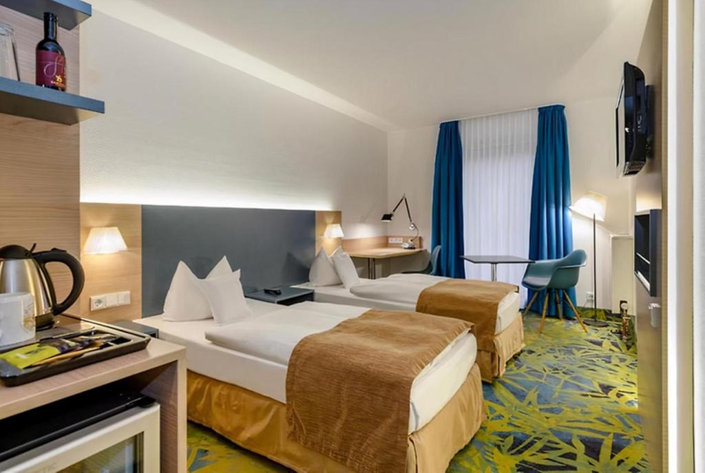 a hotel room with two beds and a television at PLAZA INN Regensburg in Regensburg