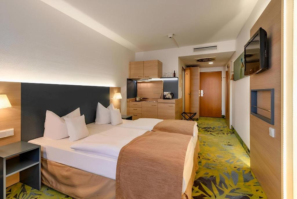 a hotel room with a large bed and a kitchen at PLAZA INN Regensburg in Regensburg
