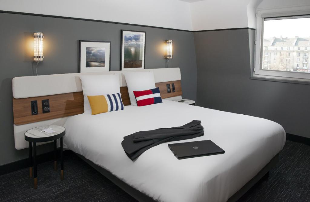 a bedroom with a large white bed with a laptop on it at Mercure Caen Centre Port De Plaisance in Caen